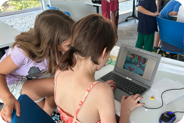Two girls looking at laptop coding in Python at Boolean Girl Summer camp